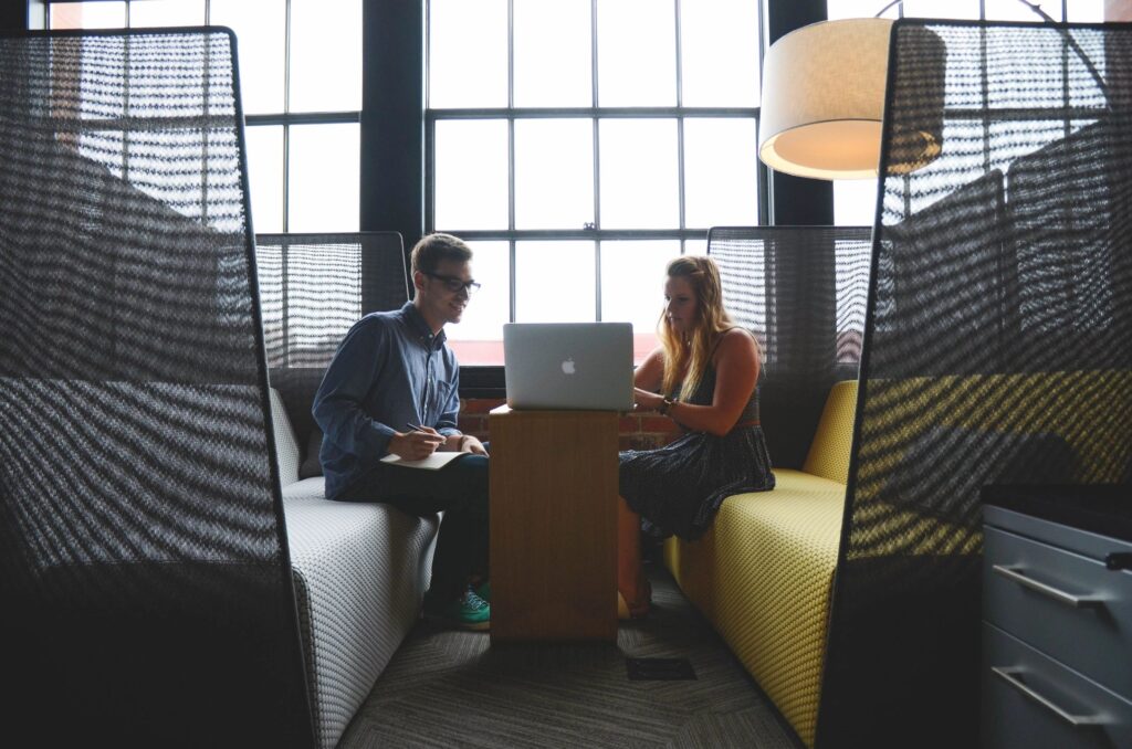 man and woman talking over a laptop